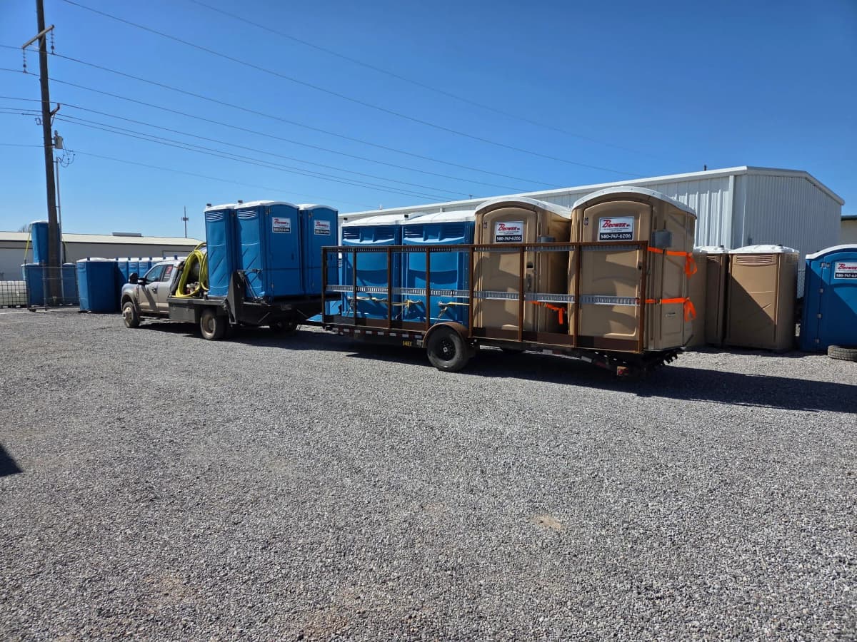 Trailer loaded with Brower Inc. portable restrooms in the yard
