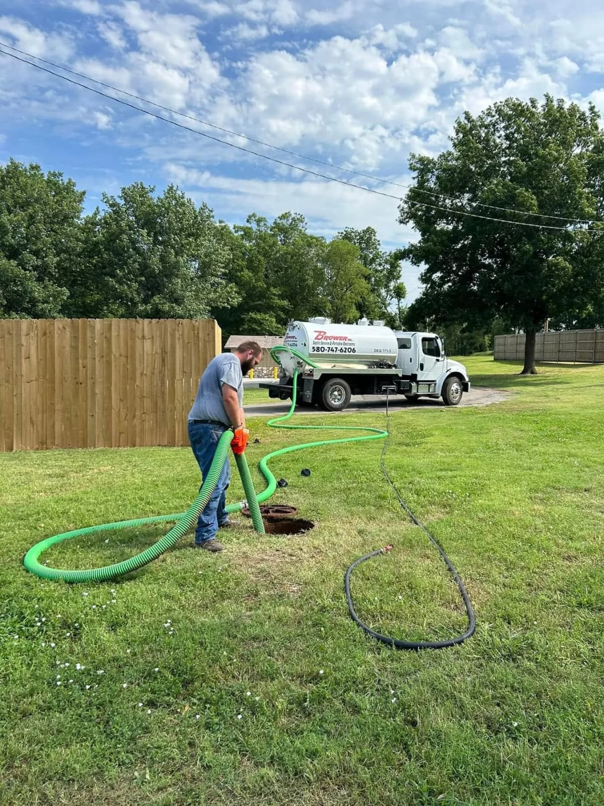 Brower Inc. technician performing septic tank pumping service at residential property in Oklahoma