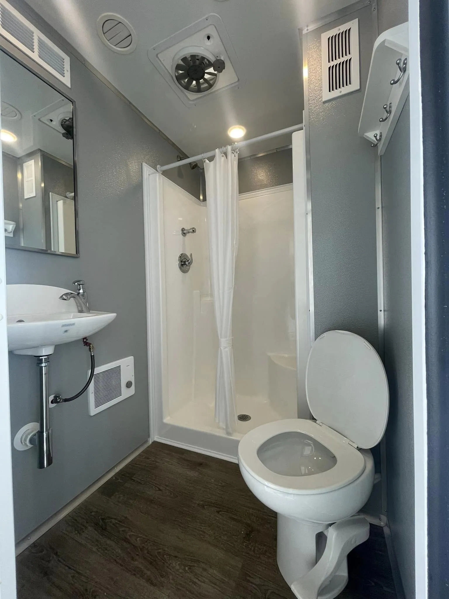 Private bathroom stall inside a Brower Inc. luxury restroom trailer — climate-controlled, flushing porcelain toilets for Oklahoma wedding venues