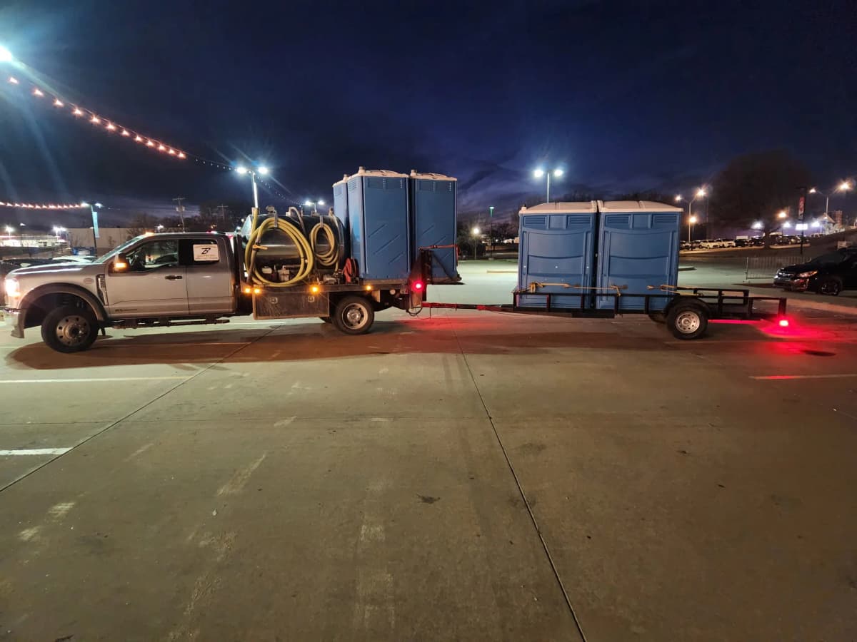 Brower Inc. truck and trailer hauling portable restrooms at night